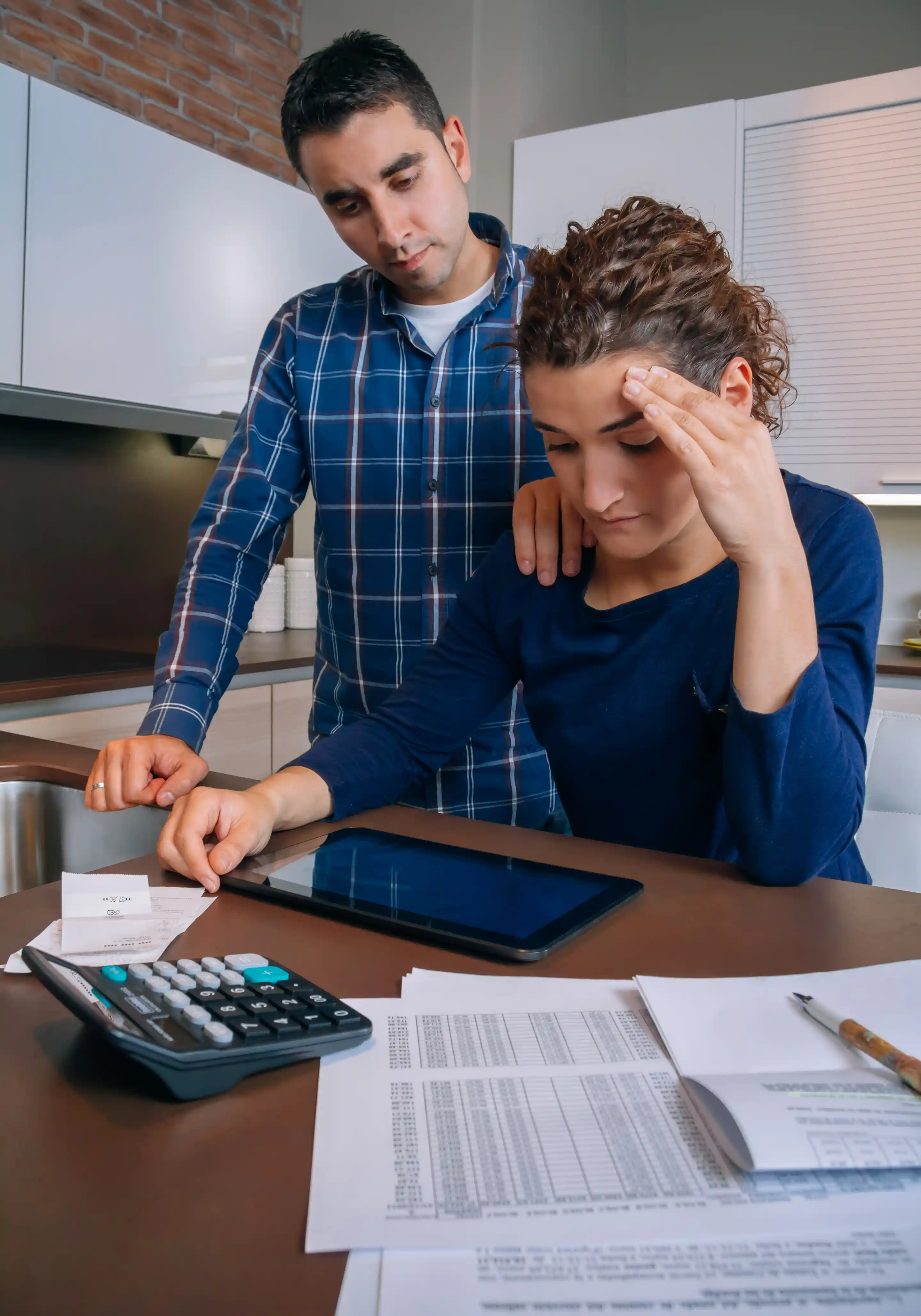 Couple stressed about finances while reviewing bills and documents at night