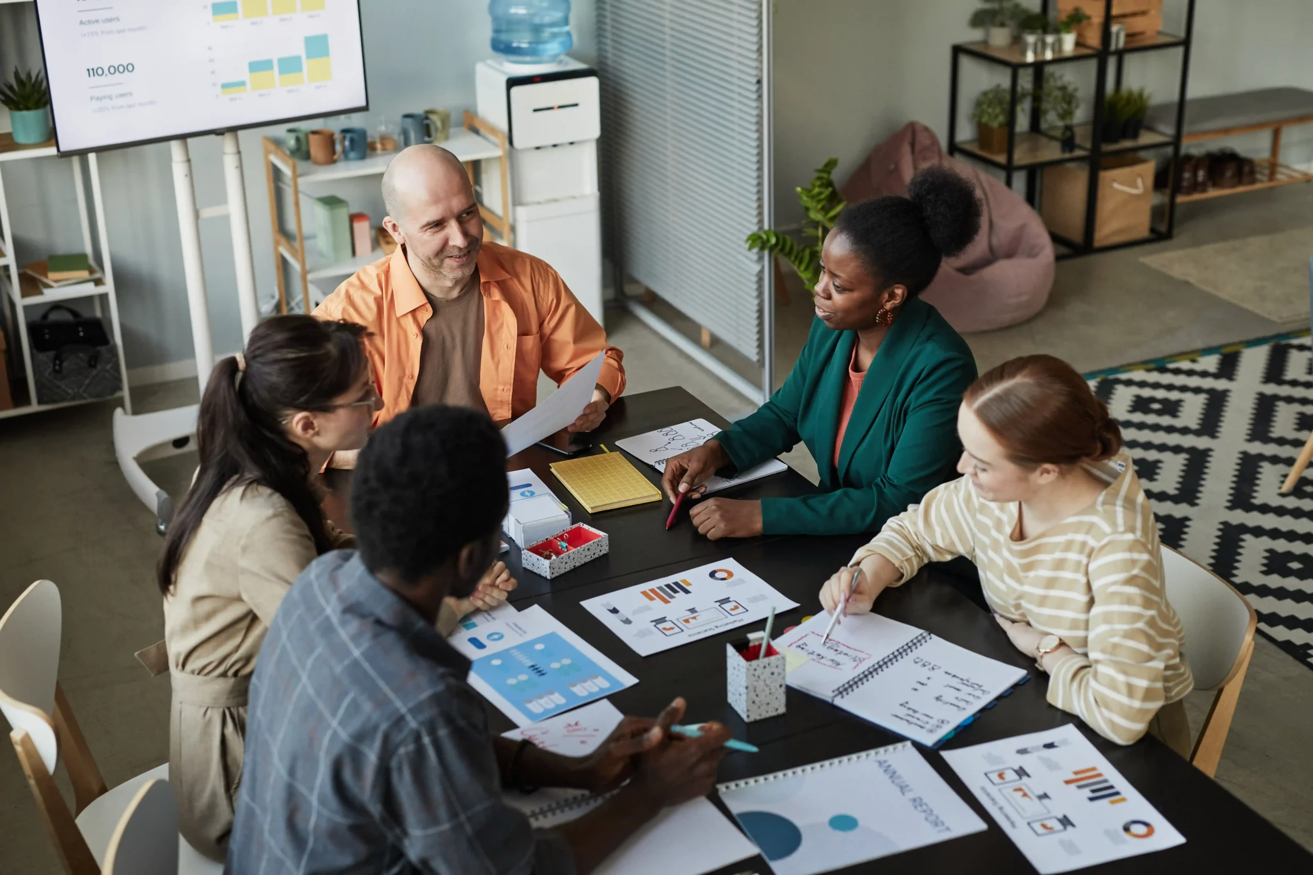 Business professionals reviewing analytics on laptop and tablet during team meeting