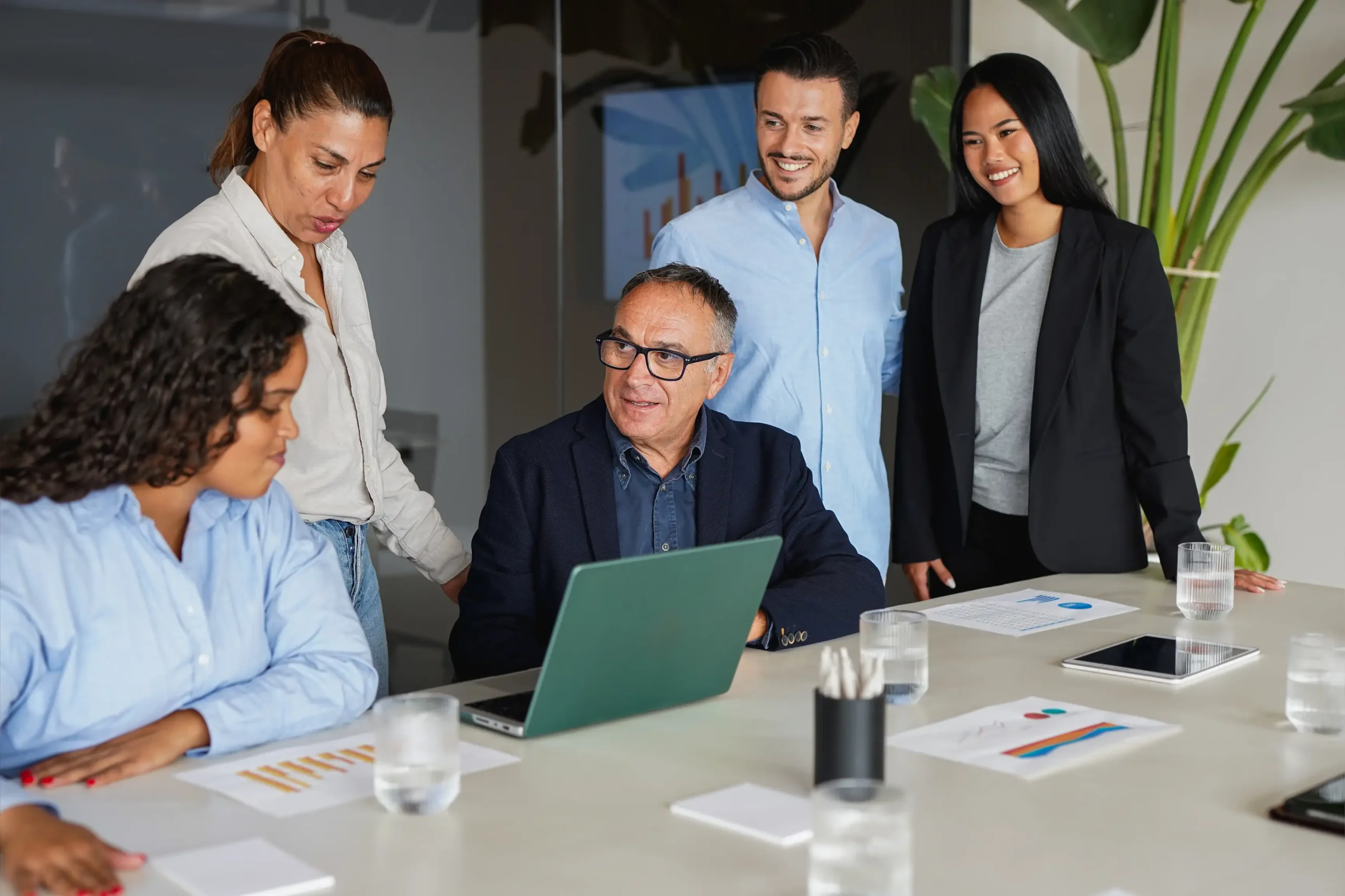Team collaborating around laptop reviewing project results in office